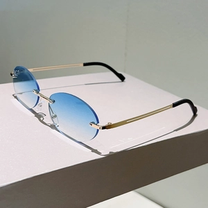 Detail view of oval rimless sunglasses with blue gradient lenses and thin gold metal temples
