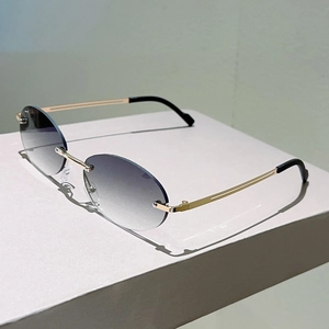 Detail of rimless oval sunglasses with gradient blue lenses and golden metal temples