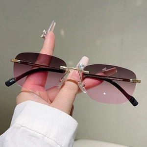 Dettaglio del ponte in metallo dorato con strass su occhiali da sole senza montatura viola