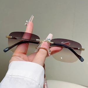 Dettaglio ravvicinato degli occhiali da sole dorati senza montatura con strass a cuore