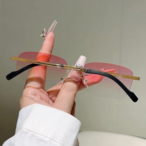 Dettaglio occhiali da sole a giorno con lenti rosa sfumate e montatura in metallo oro