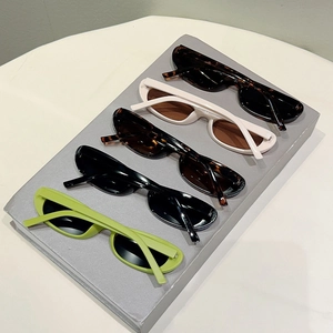 Detail view of oval vintage sunglasses in green, black, tortoise, and cream finishes