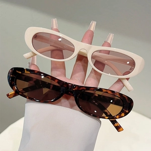 Detail view of oval vintage sunglasses in cream and tortoise shell frames with tinted lenses