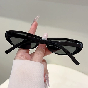Close-up of minimalist black oval sunglasses with retro narrow frames for women