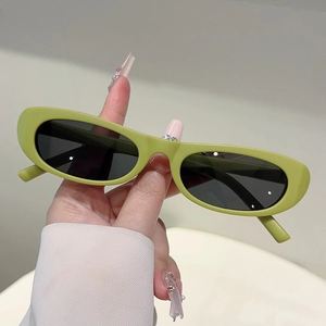 Detail view of avocado green oval sunglasses with sleek matte finish and dark lenses