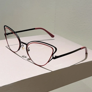 Detail of cat-eye glasses showing red and black layered metal frame design and temples