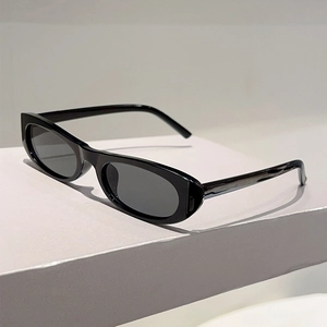 Detailed close-up of retro oval black sunglasses on a minimalist white display stand