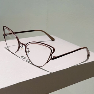 Detail view of cat-eye metal glasses frame with unique double-rim design in dark red