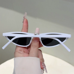 Close-up of white cat-eye sunglasses with dark lenses held against a neutral background