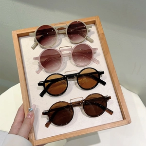 Détails de lunettes de soleil rondes vintage en quatre couleurs sur plateau en bois