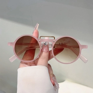 Détail de lunettes de soleil rondes rose mat avec double pont doré et verres dégradés