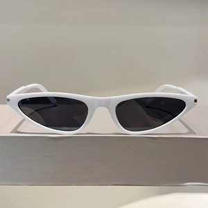Detail shot of futuristic white Y2K cat-eye sunglasses with dark grey lenses on a stand