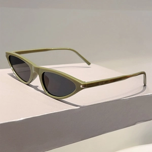 Close-up of avocado green cat-eye sunglasses with dark lenses on a white pedestal