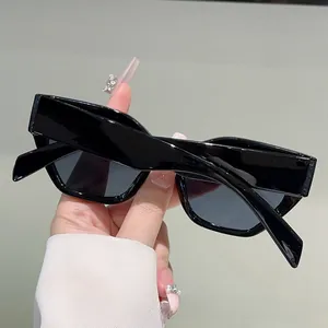 Detail view of wide black acetate frames and grey tinted lenses of cat-eye sunglasses