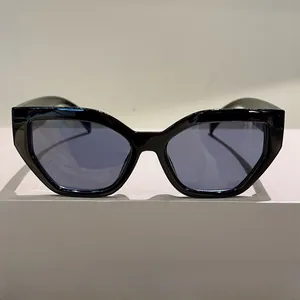 Detail view of stylish black polygon cat-eye sunglasses with dark grey lenses and glossy finish