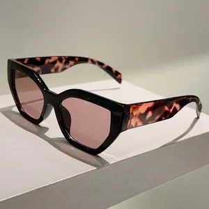 Detail of cat-eye sunglasses featuring black frames and tortoise temples with pink lenses