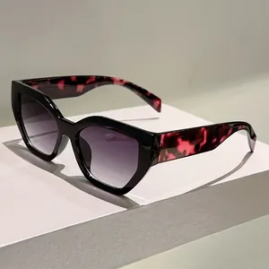 Detail of cat eye sunglasses showing black frame with red pink tortoiseshell temples