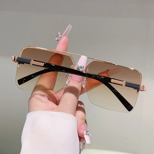 Detail of square sunglasses with brown gradient lenses and gold-black metal frame