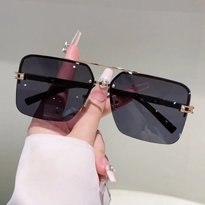 Detail of square oversized sunglasses with gold metal double bridge and dark lenses