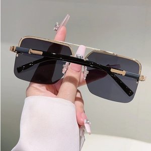 Detail of square semi-rimless sunglasses featuring gold metal frame and black temple tips