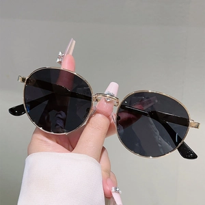 Close-up of hand holding round metal frame sunglasses with dark polarized lenses