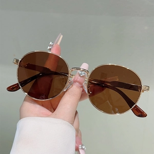 Detailed macro view of gold metal sunglasses with brown lenses and tortoiseshell temple tips