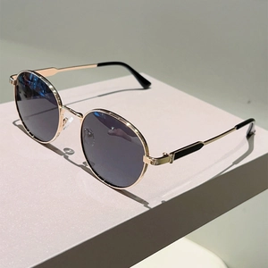 Detail of vintage round sunglasses with slim gold metal frame and dark grey lenses