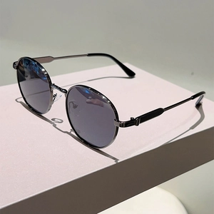 Close-up of classic round metal sunglasses with dark lenses on a geometric display stand
