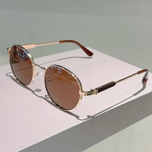 Close-up of retro gold metal frame sunglasses with brown round lenses on a display stand