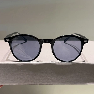 Detail view of retro black full-rim sunglasses with silver metal rivets on display stand