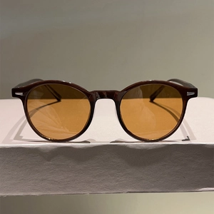 Retro round frame sunglasses with tortoiseshell frame and amber lenses on a display