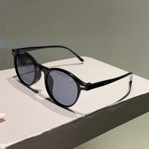 Detailed close-up of classic black round-frame sunglasses with silver metal rivets and grey lenses