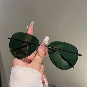 Détail de lunettes de soleil aviateur polarisées sans monture vert foncé tenues à la main