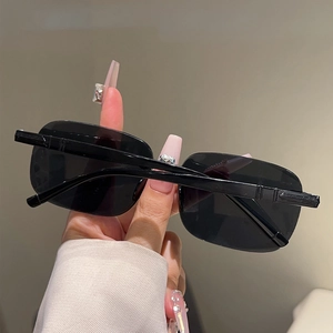 Détail de lunettes de soleil carrées sans monture avec verres noirs et charnière métal