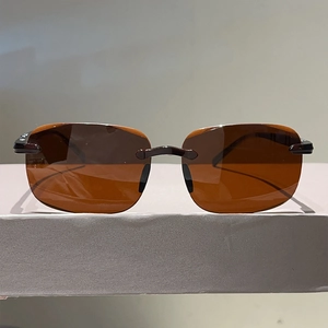 Détail de lunettes de soleil sans monture avec verres bruns et charnières métalliques fines