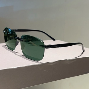 Détail de lunettes de soleil carrées sans monture avec verres vert foncé et branches fines