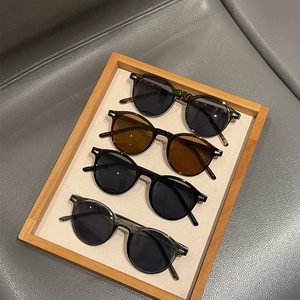 Retro round frame sunglasses set in four colors with silver rivet accents on a tray