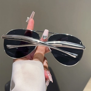 Close-up of silver metal double-bridge pilot sunglasses held by hand with dark lenses