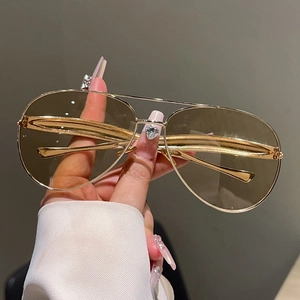 Detail of pilot sunglasses with gold metal double bridge and light brown lenses
