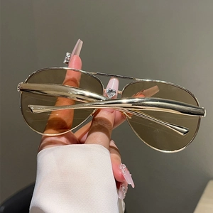 Detail of trendy aviator sunglasses with gold double-bridge frame and brown gradient lenses