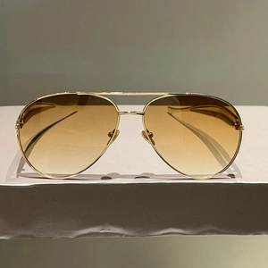 Detail of aviator sunglasses with gold metal frame and gradient brown lenses