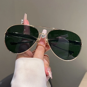 Detail of aviator sunglasses with gold metal double bridge and dark lenses on hand