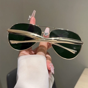 Close-up of golden double-bridge aviator sunglasses with dark lenses for a trendy street look