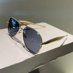 Detail of aviator sunglasses with gold metal frame and brushed texture on temples