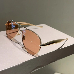 Detail of rose gold aviator sunglasses with brown gradient lenses on a minimalist stand