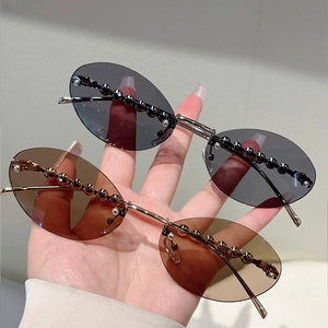 Detail of oval rimless sunglasses featuring metal bead trim and slim golden temples