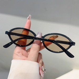 Vue détaillée de lunettes de soleil ovales noires avec verres teintés marron à la main