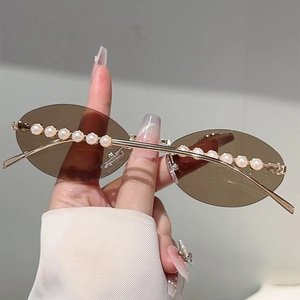 Detail of oval rimless sunglasses with brown lenses and white pearl embellishments