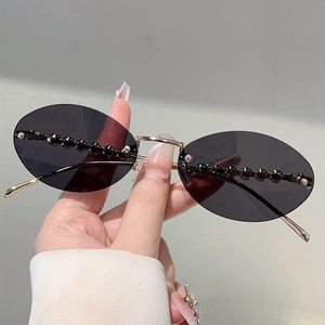 Detail of oval rimless sunglasses with gold metal frame and black bead decorations
