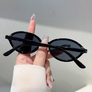 Détail de lunettes de soleil ovales vintage avec monture noire et verres teintés foncés